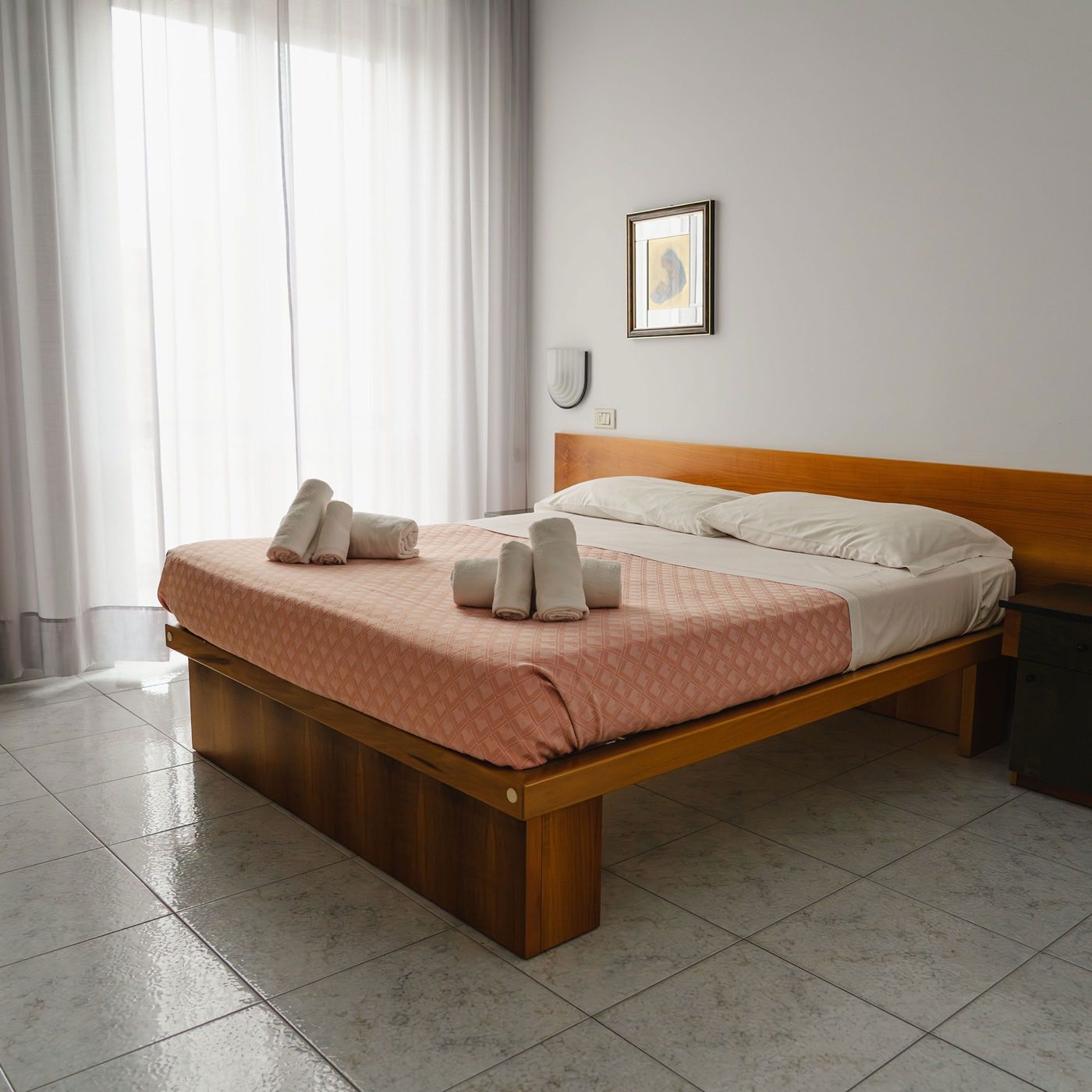Camera matrimoniale con letto in legno e asciugamani di benvenuto